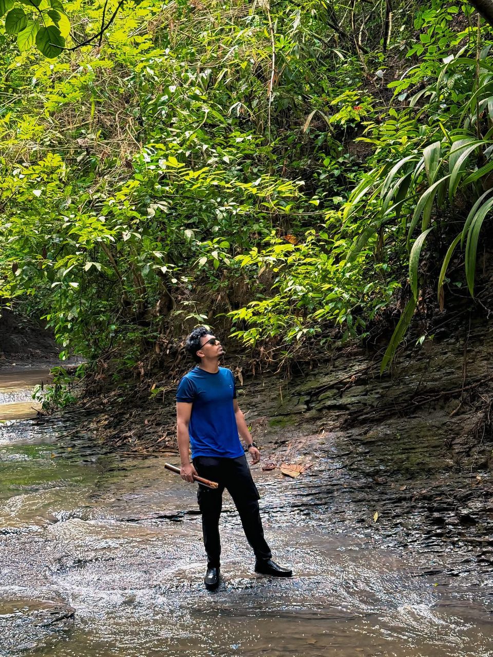 Shahriar beside a wooded stream